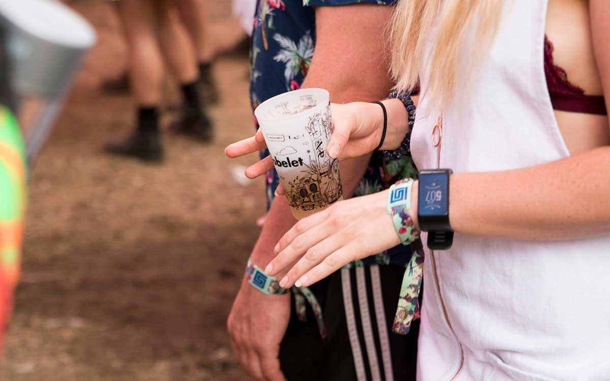 Festival attendee wearing cloth RFID event wristband while holding a drink at outdoor event in Canada
